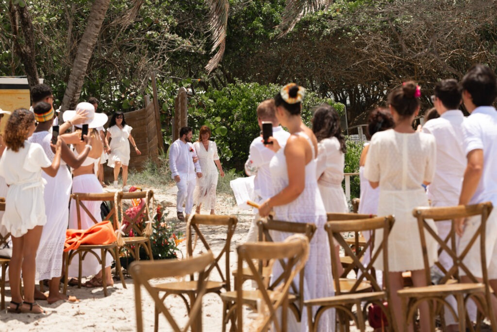 Chaises croisées en bois alignées sur le sable pour cérémonie de mariage en Martinique